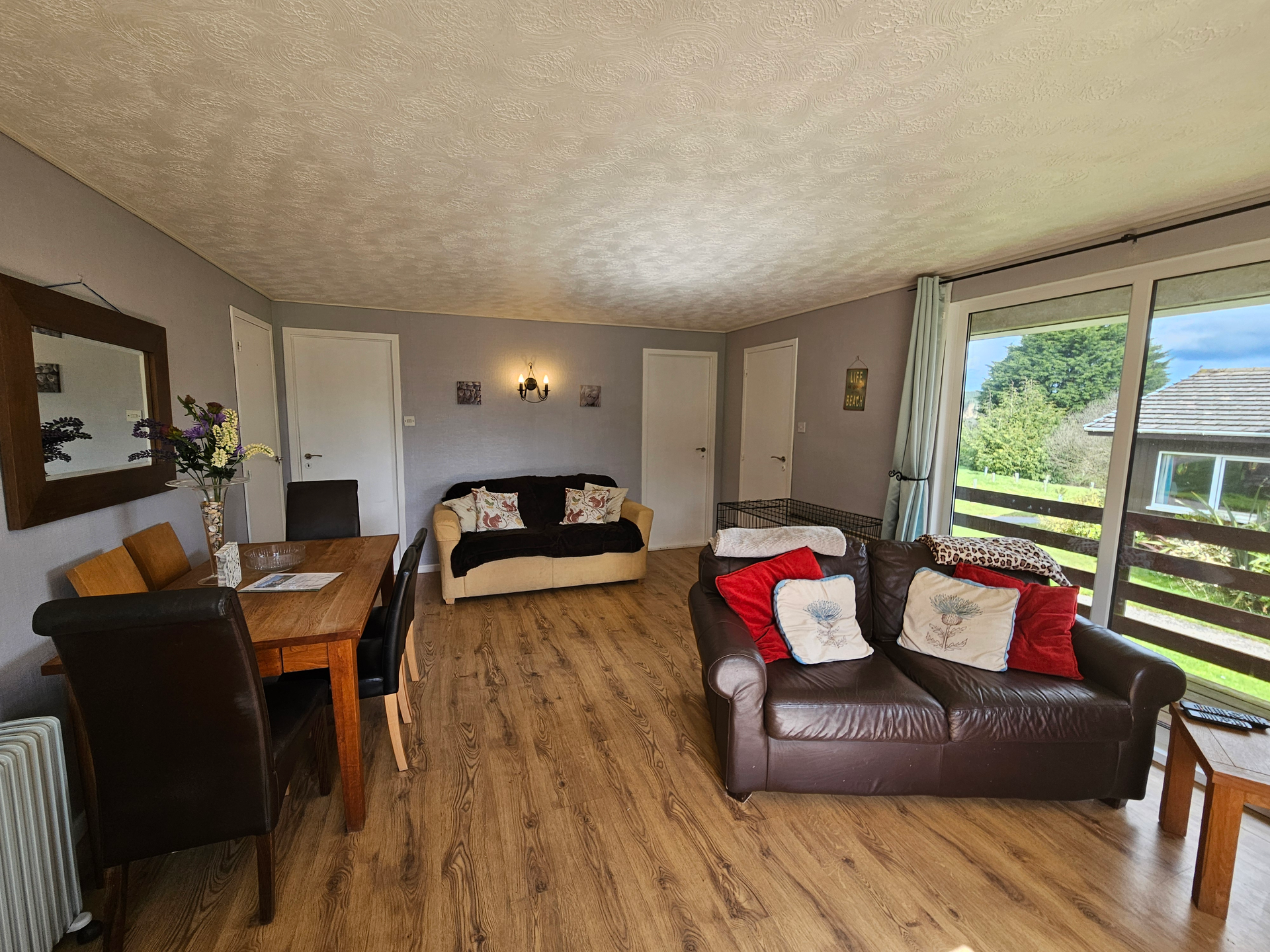 A spacious living area which has a dining table, two sofas, and a handy dog cage