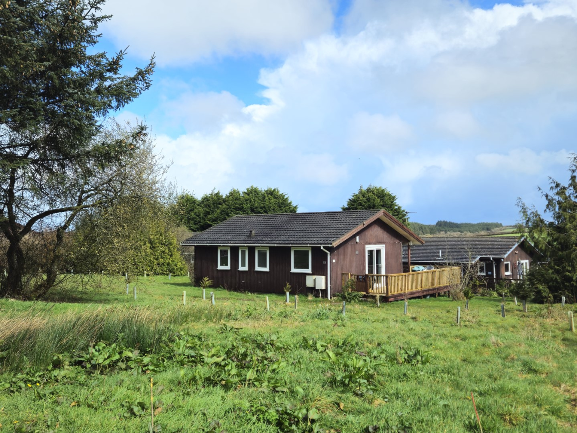 The wooden lodge, which has a large decking area, with a BBQ and table on it
